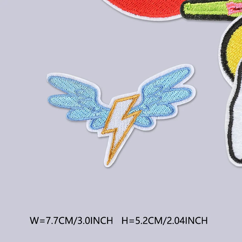 A light blue embroidered butterfly with a yellow lightning bolt on a gray background.