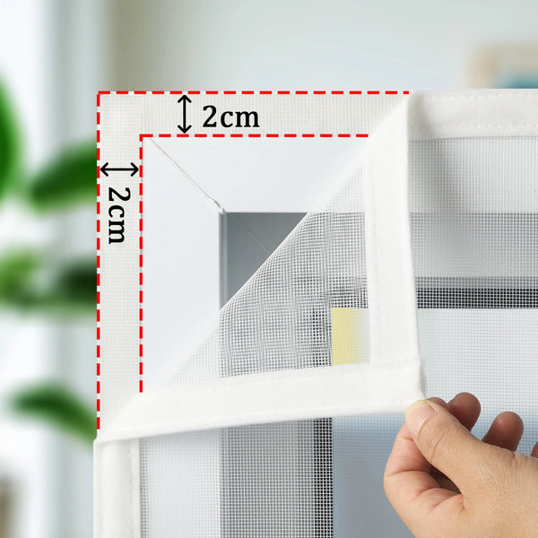 A close-up of a white self-adhesive window screen being measured and installed in a window frame.