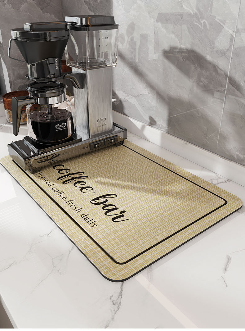 A silver insulated coffee cup drainer mat is placed on a white marble surface next to a coffee grinder.