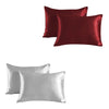 A set of two satin silk pillowcases, one deep burgundy and one silver gray.