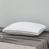 A white luxury goose down and feather bed pillow resting on a gray fabric surface.