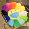 A round, yellow sunflower plush cushion with a smiling face surrounded by colorful, fluffy fabric petals in a gold wire baske