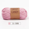 A skein of pink sweet candy yarn with a brown label is shown lying horizontally.