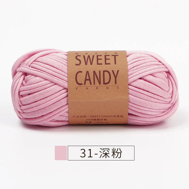 A skein of pink sweet candy yarn with a brown label is shown lying horizontally.