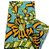 Close-up of an African wax print fabric featuring a vibrant pattern of yellow, green, and blue on a black background.