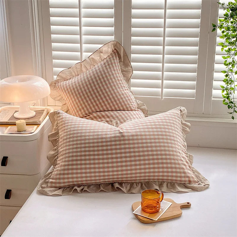 Two soft plaid washed cotton pillowcases with ruffled edges resting on a white surface.