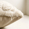 A close-up of a beige fuzzy maple leaf throw pillow cover with a white fluffy texture.
