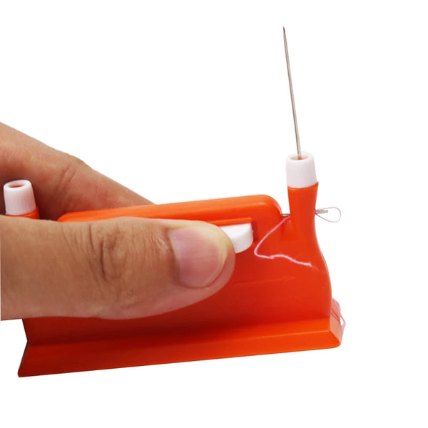 A hand holds an orange automatic double-head sewing needle threader with a thin metal needle.