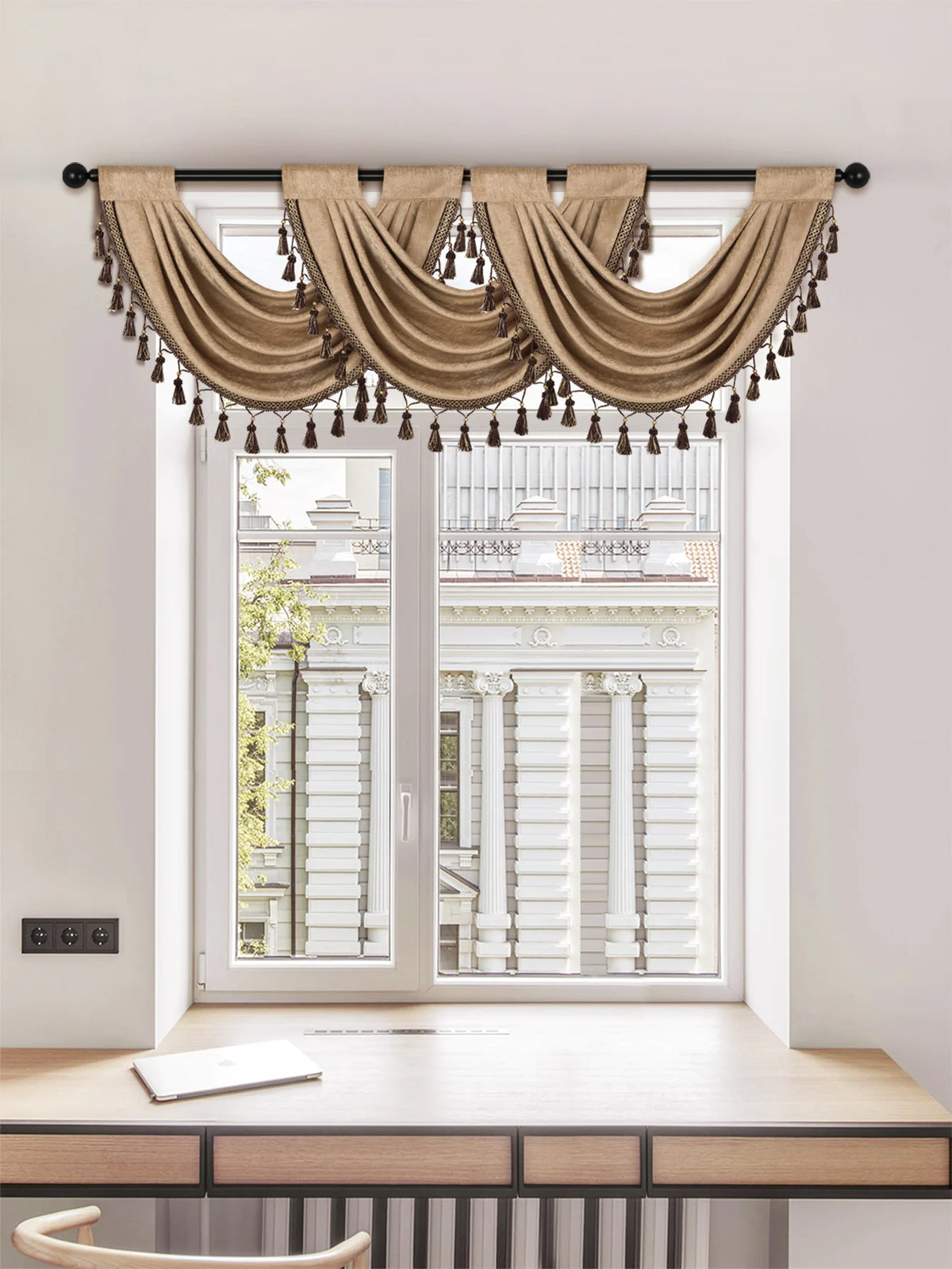 A beige European style window curtain valance with tassels hanging over a white door frame.