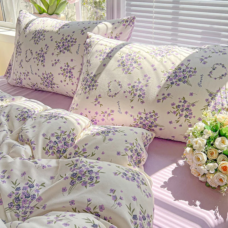 A set of lavender print duvet covers and pillowcases with floral patterns displayed on a bed.