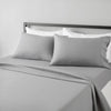 A gray fitted sheet set with white pillowcases is displayed on a bed with a dark headboard.