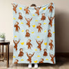 A light blue flannel throw blanket featuring repeating illustrations of Curious George monkeys