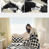 A black and white checkered flannel blanket with a soft, fluffy texture is displayed on a bed.