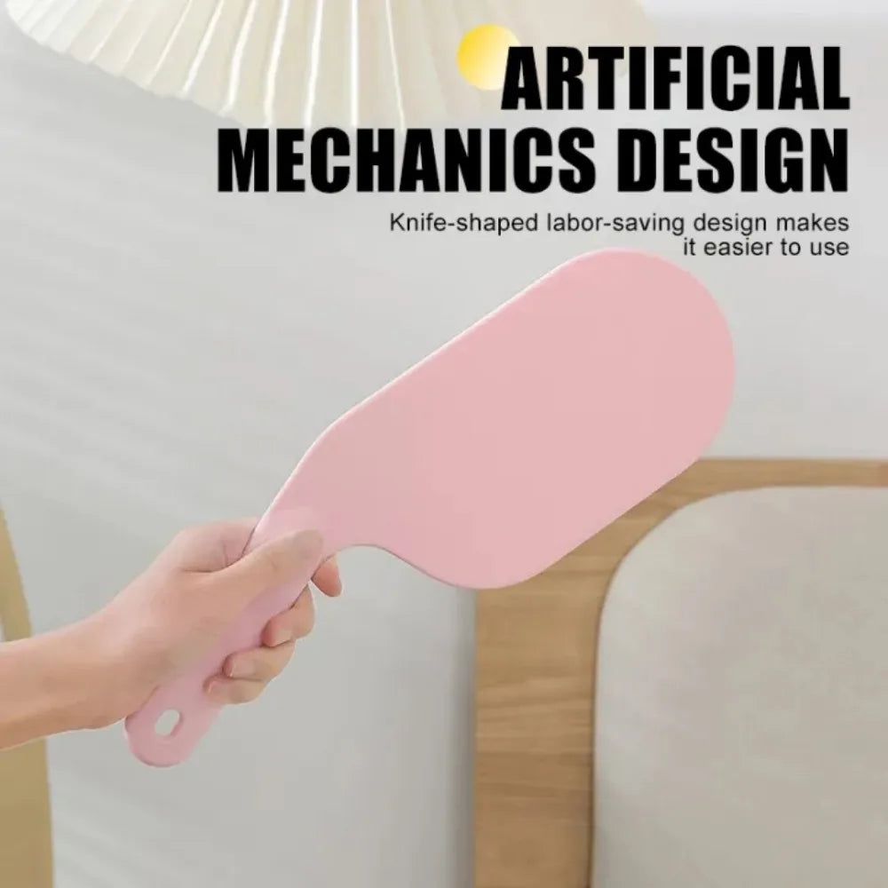 A hand is using a pink knife-shaped tool for bed sheet folding and organizing.