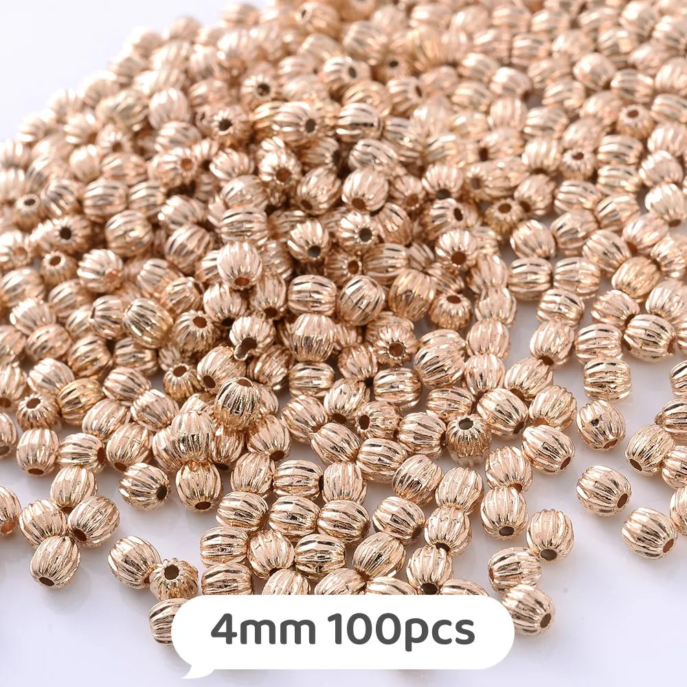 A pile of small, round, gold-colored geometric acrylic beads for jewelry making