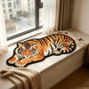 An orange and black tiger plush cartoon area rug displayed on a white windowsill next to draped fabric.