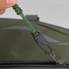 A close-up of a green braided cord with a black slider attached to a dark olive canvas bag.