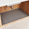 A silicone under sink cabinet liner installed in a wooden cabinet with a stainless steel faucet.