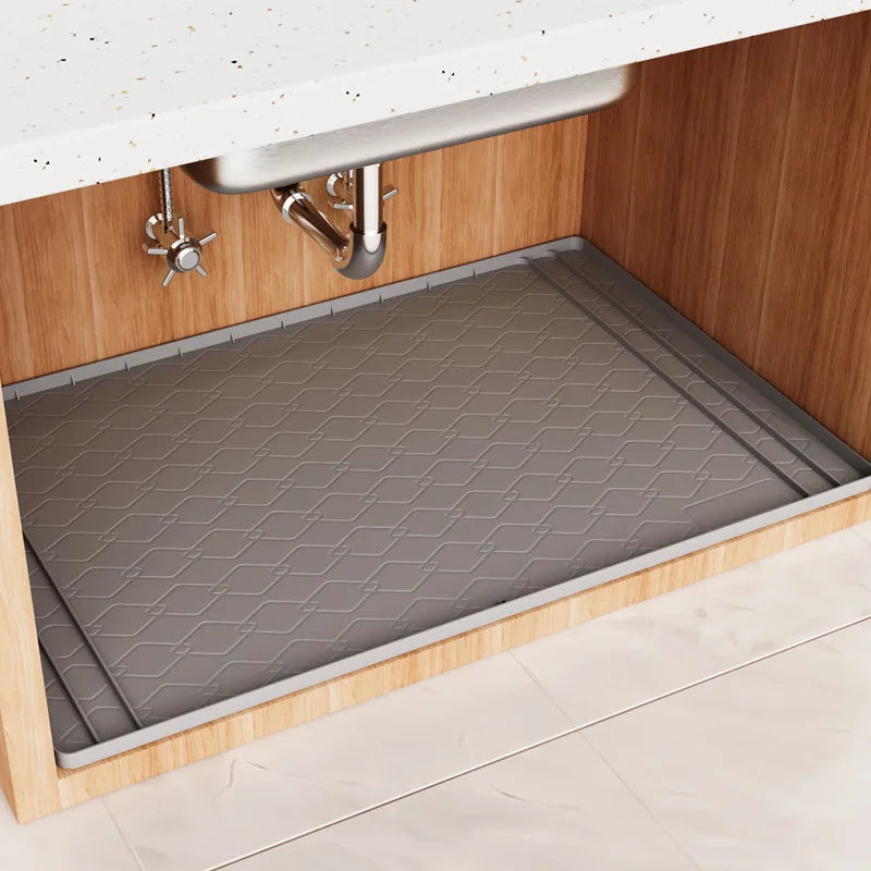 A silicone under sink cabinet liner installed in a wooden cabinet with a stainless steel faucet.