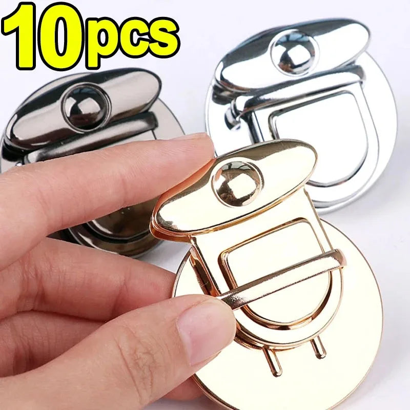 A hand holds a gold metal twist lock for bags and cases, showing the detail of the small locking mechanism.