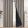 A floor-length gray and black blackout curtain hanging in a window frame.