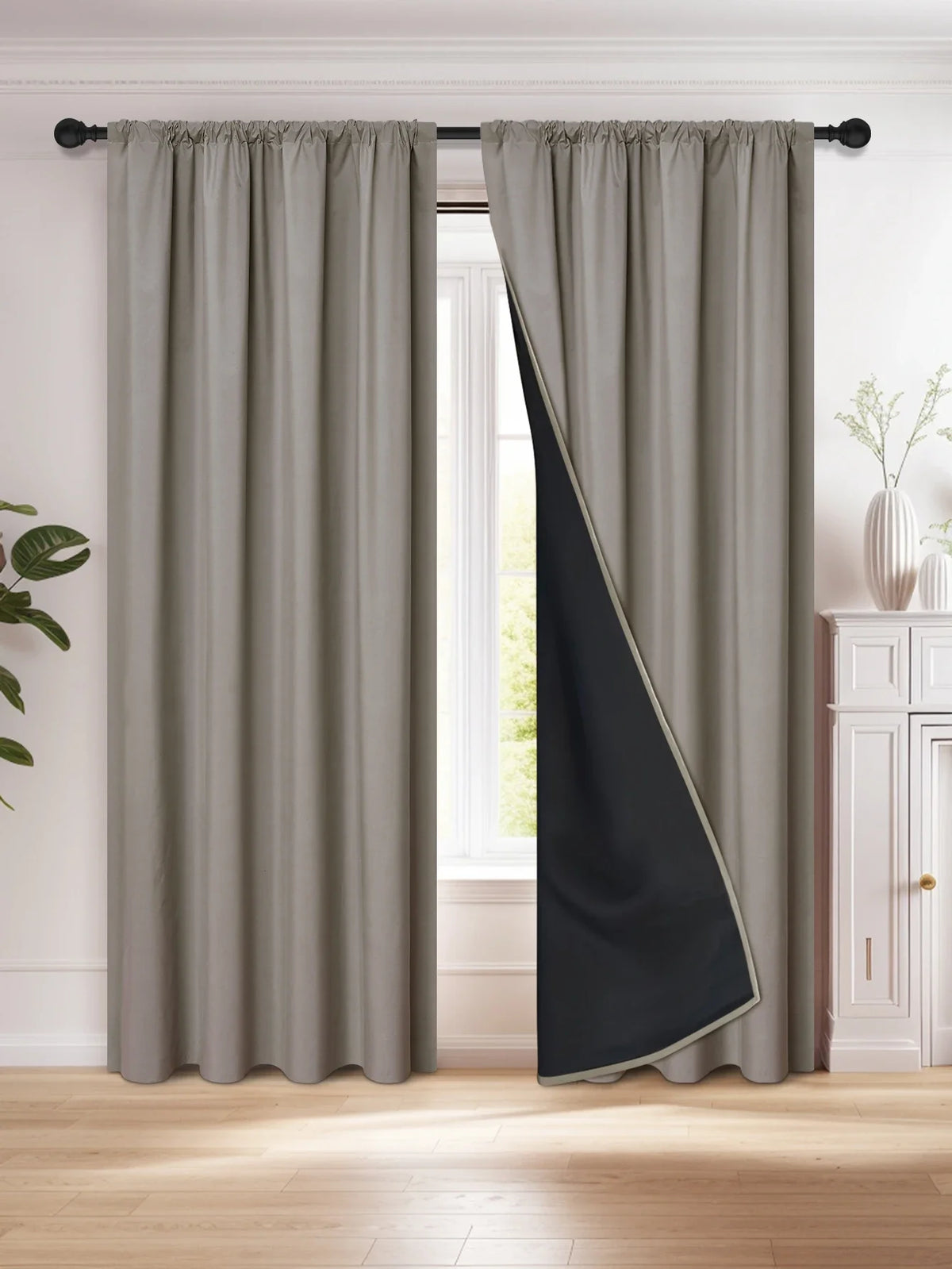 A floor-length gray and black blackout curtain hanging in a window frame.