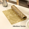 A golden woven table runner with a leaf pattern rolled up on a light surface.