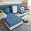 A light blue jacquard elastic sofa slipcover with white accents and pillows on a modern living room floor.