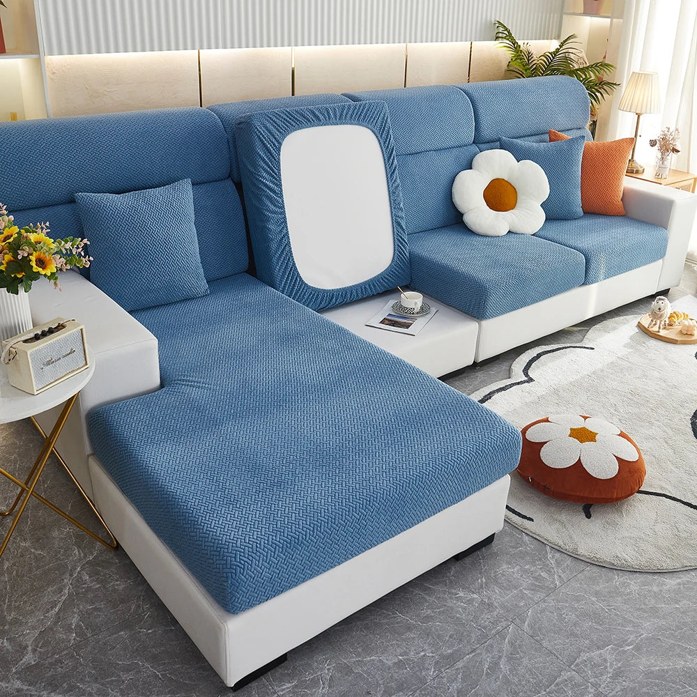 A light blue jacquard elastic sofa slipcover with white accents and pillows on a modern living room floor.