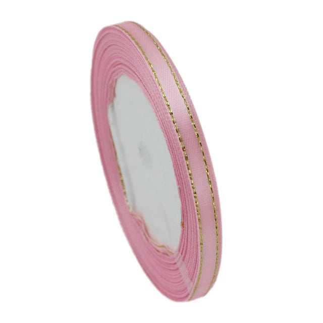 Pink satin ribbon with gold edges rolled into a cylinder for gift wrapping and crafts