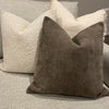 A dark brown linen textured throw pillow resting on a light gray sofa with cream-colored pillows.