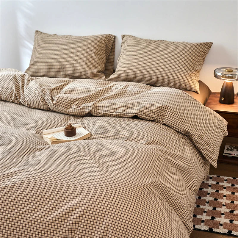 A beige plaid duvet cover set with matching pillows and a wooden bedside lamp.