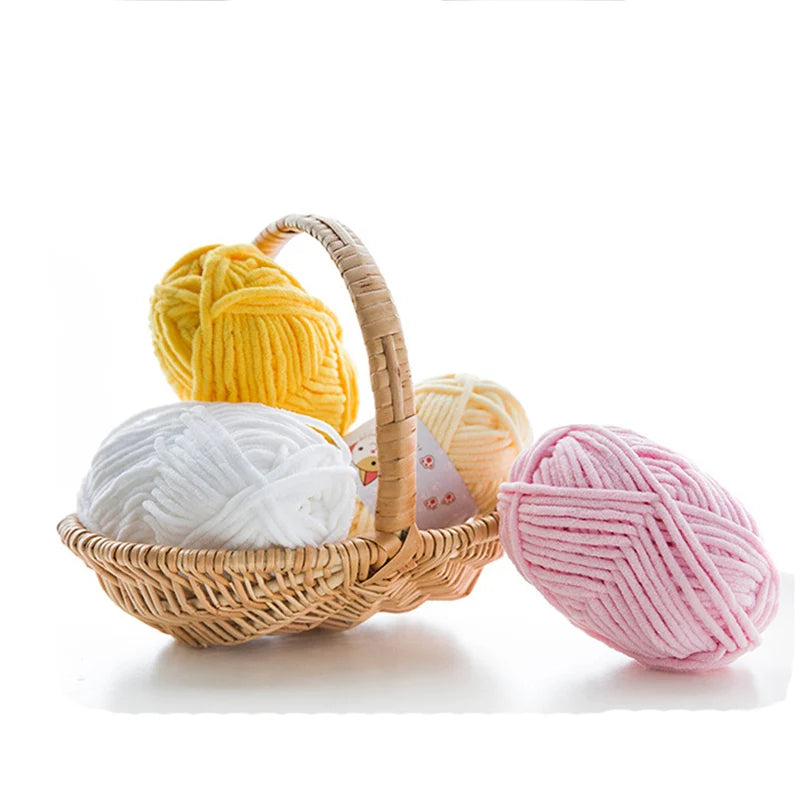 A basket holds several skeins of thick velvet yarn in yellow, white, and pink colors.