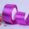 A roll of vibrant purple satin craft ribbon with a white fluffy center core.