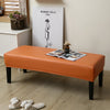An orange waterproof stretch dining bench cover placed on a wooden floor in a room with a framed artwork.