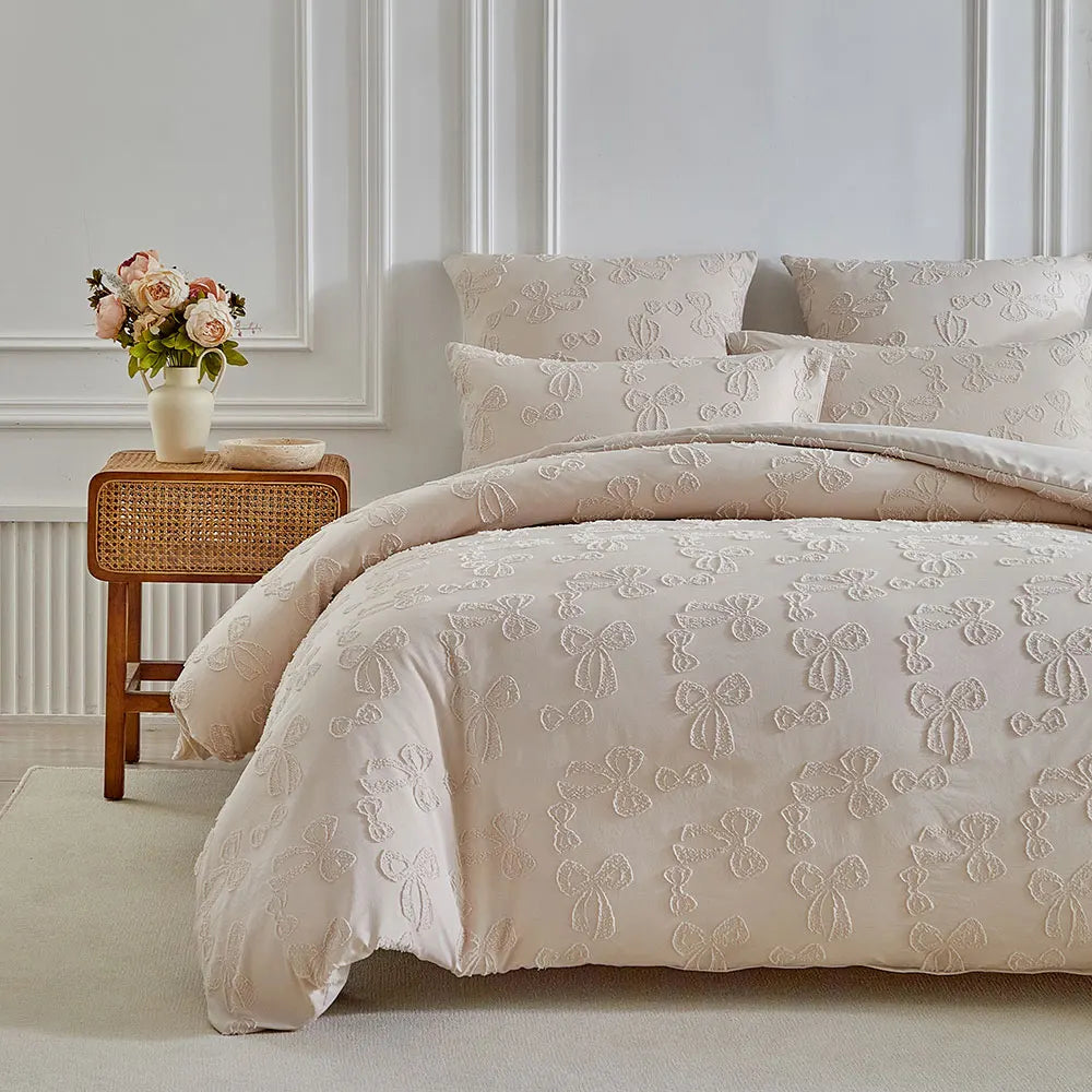 A luxury duvet set featuring a cream-colored quilt with delicate white embroidery on a bed in a bright room.