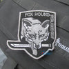 A gray uniform patch featuring a stylized foxhound wolf head design and the text FOX HOUND.