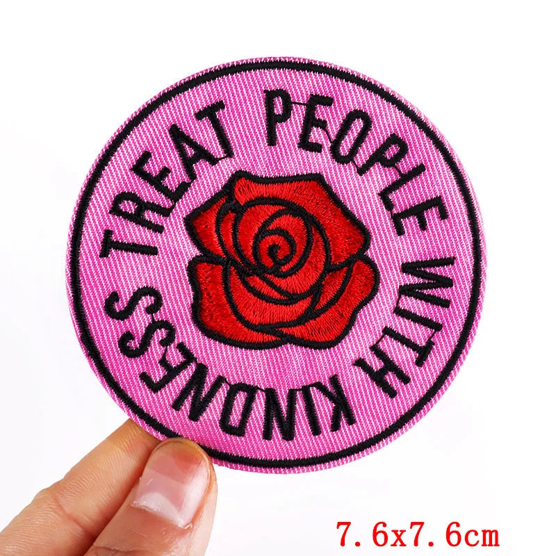Pink letter embroidered iron-on patch with the text Treat People With Kindness on a circular background