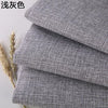 Stack of gray coarse linen and cotton fabric rolls with dried wheat stalks