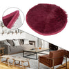 A deep burgundy shaggy round area rug displayed on a modern living room floor.