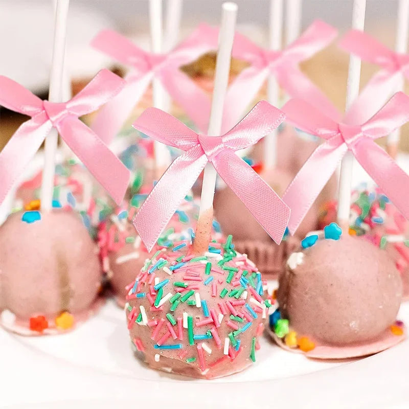 Pink cake pops decorated with sprinkles and tied with pink satin ribbon bows
