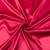 A vibrant magenta satin bedding set with fitted sheets, tightly rolled to show the fabric's sheen.