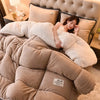 A woman is relaxing under a plush double-sided fleece blanket in beige and cream tones.