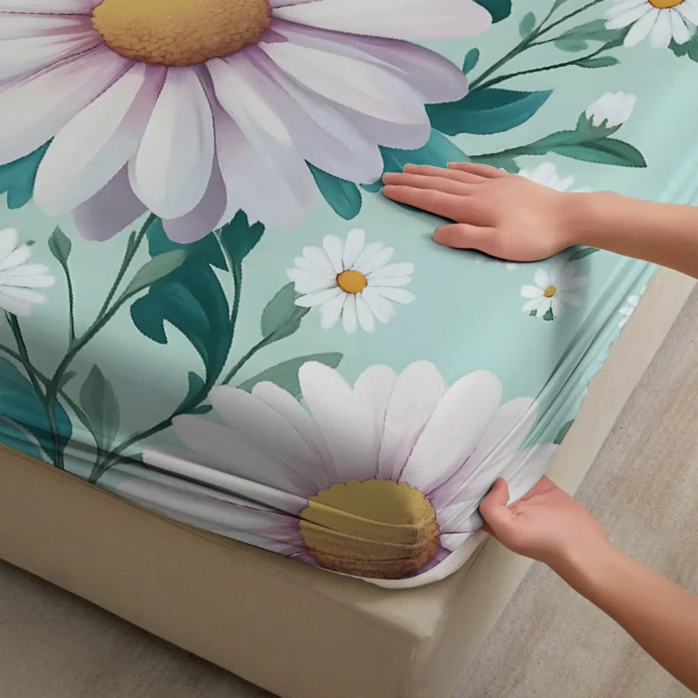 A hand gently touches a fitted mattress protector sheet featuring a white and purple floral print on a teal background.