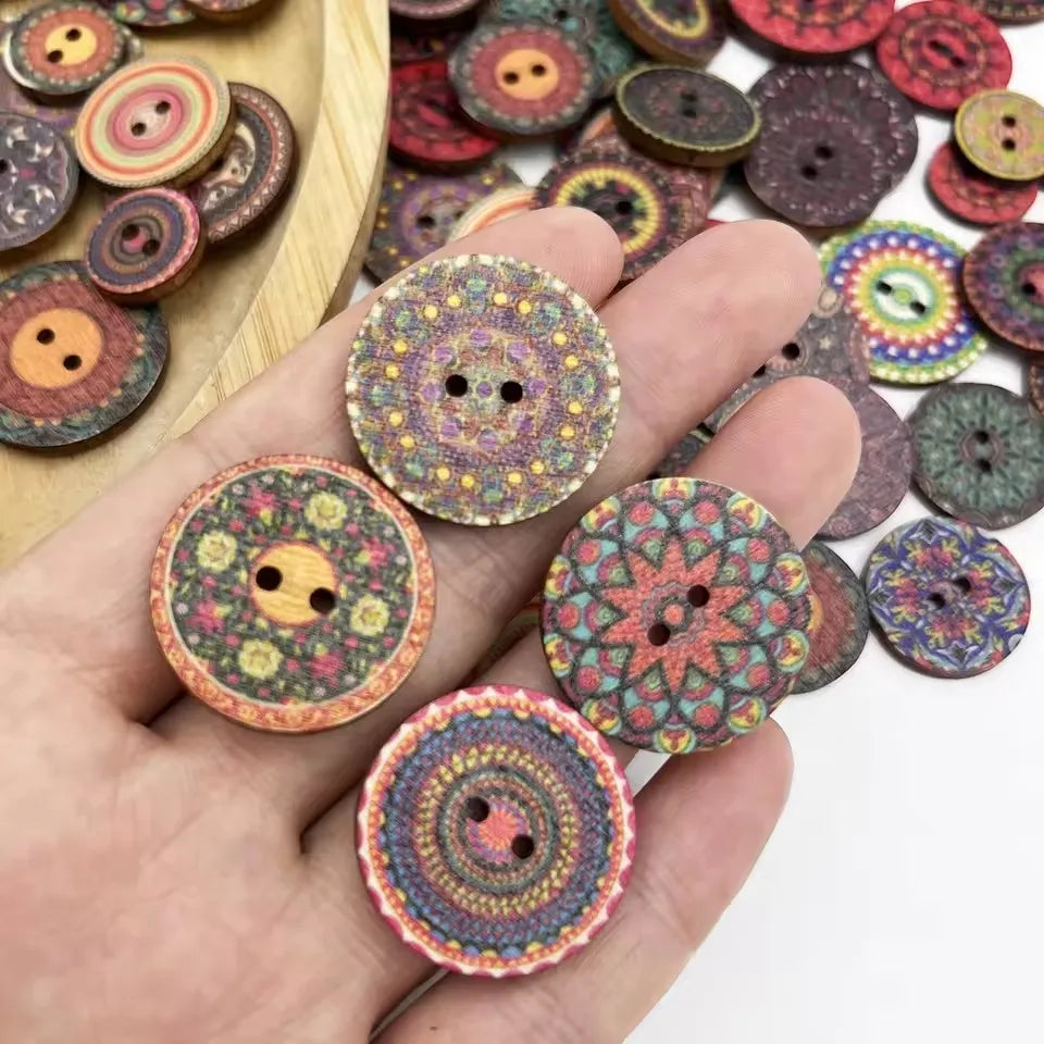 A hand holds various colorful, vintage wooden buttons and craft pieces on a light wooden surface.
