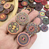 A hand holds various colorful, vintage wooden buttons and craft pieces on a light wooden surface.
