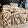 A thick, beige, fluffy blanket is draped over a bed, featuring vertical stripes and textured fibers.