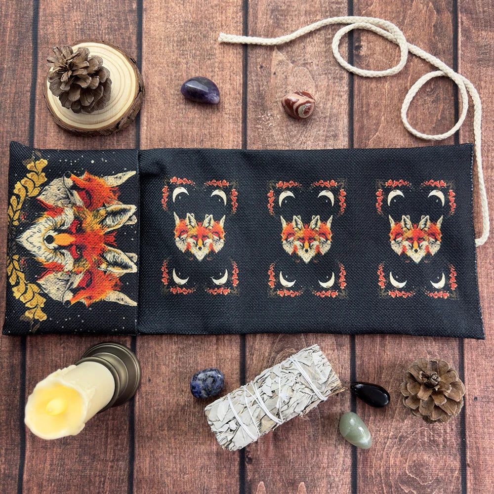 A dark fabric pouch decorated with mystical symbols and featuring natural elements like pinecones, stones, and a candle.