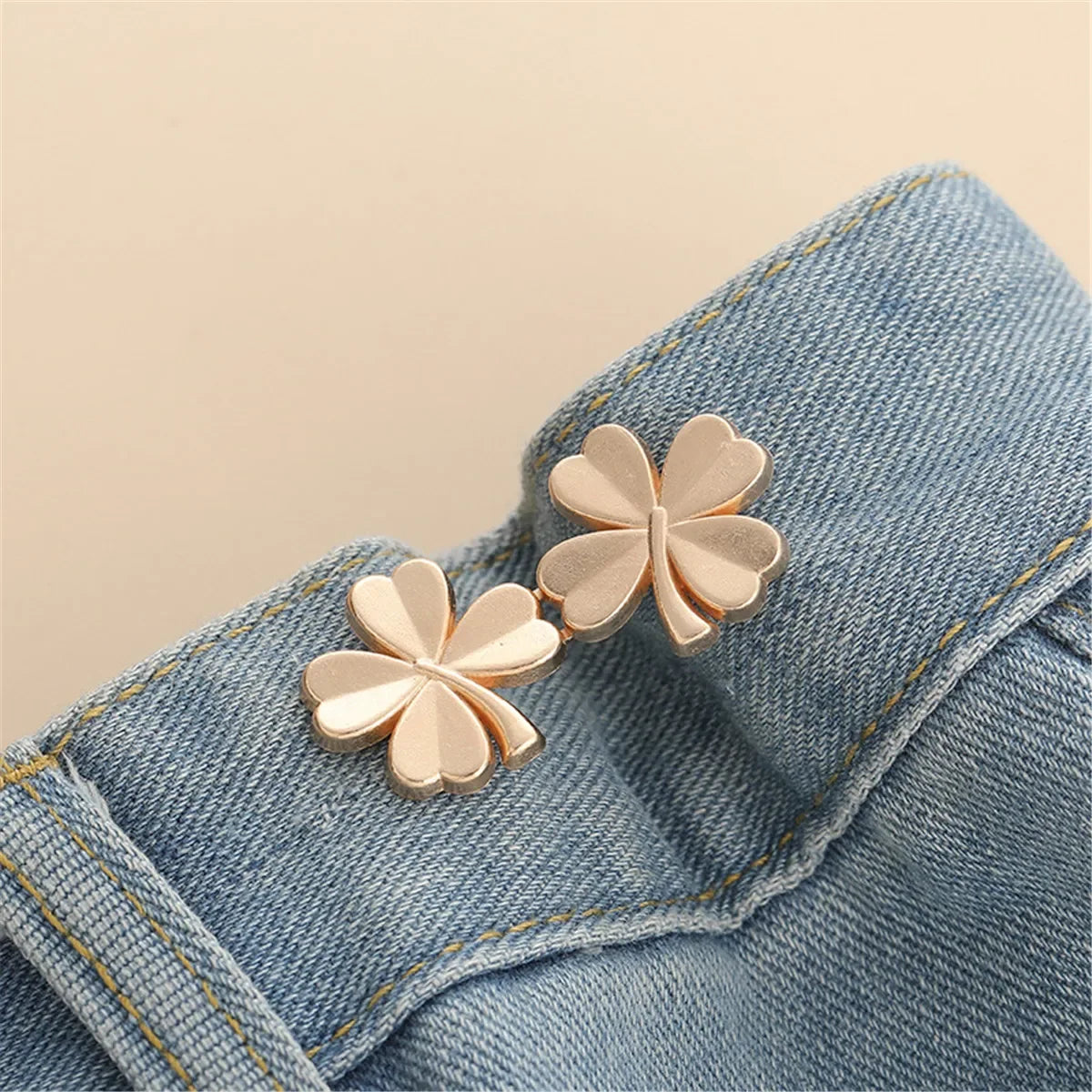Gold-toned butterfly button clips attached to a denim fabric
