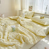 A fluffy yellow summer seersucker quilt comforter draped on a bed with a white lamp and window view.